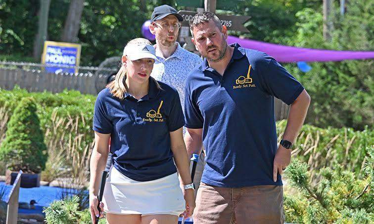 Justin and Anna Seymour in matching Ready Set Putt shirts, with Kyle Courcy behind them